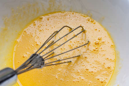Whipping yolks with a wire whiskの写真素材