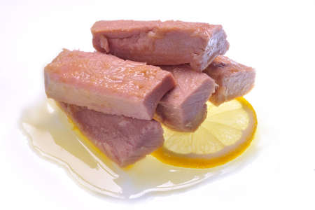 five fillets of tuna in oil on lemon slice and white background