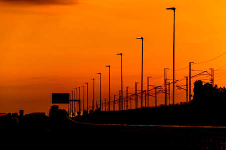 Silhouette High speed railway power line and light poles in perspective, on spectacular intense...