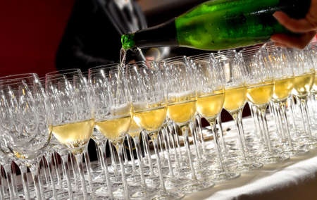 Welcome drink sommelier pours wine white sparkling wine a bottle into a glasses in the foreground. Wine tastingの写真素材