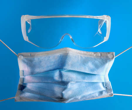 Medical mask and goggles, for covid-19 coronavirus protection, health care and medical concept. blue backgroundの写真素材
