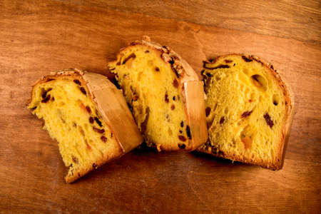 Panettone, classic Christmas cake from Milan, three slices on rustic wooden background