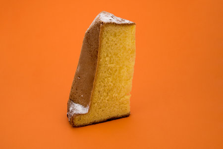 A slice with icing sugar isolated on orangeの写真素材