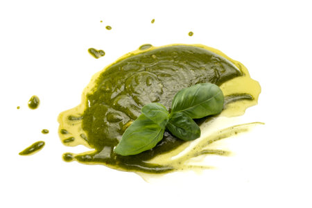 Pesto spread on a white background, typical Genoese and Ligurian sauce, with fresh green basil leaves and extra virgin olive oilの写真素材