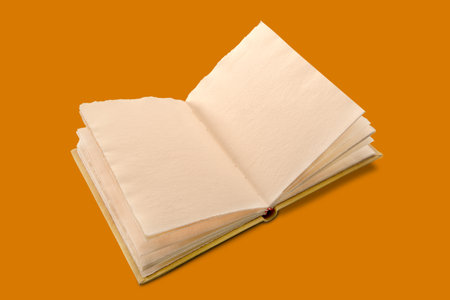 Open antique style book with pages of rough paper with jagged edges, antique leather hardcover notebook isolated on orange backgroundの写真素材