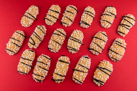 cookie with sugar grains and chocolate strips, Italian ladyfingers called tresor on red background, top view, flat layerの写真素材