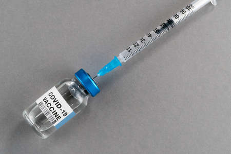 Coronavirus COVID-19 vaccine. Vial with syringe isolated on gray background, concept composition...