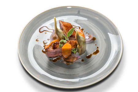 Roasted duck breast with artichokes, sage and carrots in a gray plate isolated on a white backgroundの写真素材