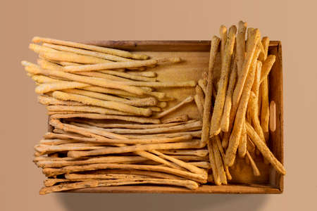 Italian breadsticks with sesame seeds and with olives in wooden tray