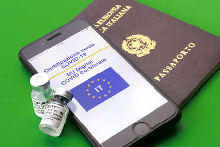TURIN, ITALY - JULY 27, 2021: Pfizer COVID-19 Vaccine Comirnaty vial on smart phone with digital green certificate of the european union with passport on green background, green pass travel conceptのeditorial素材