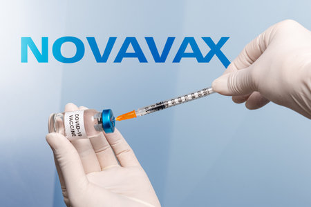 Turin, Italy - December 18, 2021: nurse hands with latex gloves with syringe that takes vaccine from vial, in the background Novavax Laboratory logo, protein vaccine, vaccination conceptのeditorial素材