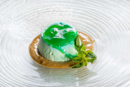 Delicious panna cotta dessert with green mint sauce and mint leaves in glass dishの写真素材