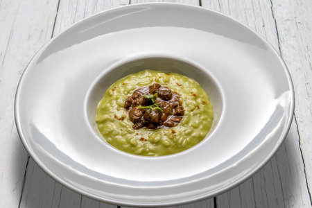 Vegetable risotto with duck stew, in a white plate on white wooden tablesの写真素材