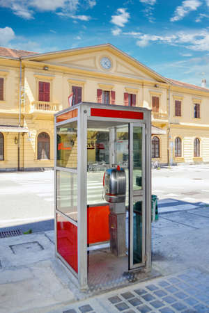 Fossano, Cuneo, Italy - July 16, 2016: Telecom Italia (TIM) phone box. Phone booth in front of the old train station buildingのeditorial素材