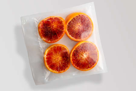 Four slices of red oranges fruit in vacuum packed sealed for sous vide cooking isolated on Gray background in top viewの写真素材