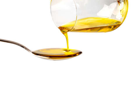 Extra virgin oil poured from glass into spoon, isolated on white background, clipping pathの写真素材