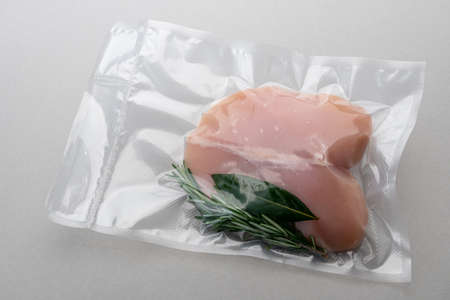 Chicken breast with rosemary and bay leaves in vacuum packed sealed for sous vide cooking isolated...