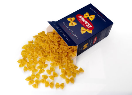 Turin, Italy - october 15, 2022: Macaroni farfalle pasta Barilla, bow tie shaped pasta come out of blue package isolated on white, Barilla is world famous Italian pasta factoryのeditorial素材