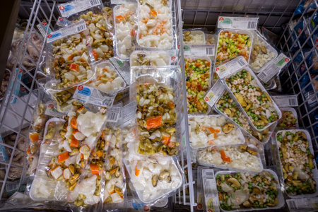 Italy - January 08, 2023: Seafood salads with prawns and vegetables, mussels, squid and frozen molluscs in packs in refrigerated counter for sale in Italian supermarketsのeditorial素材