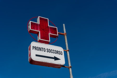 Italy - January 03, 2023: Italian first aid sign with red cross on blue sky, tex: Pronto Soccorso (first aid), copy spaceのeditorial素材
