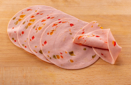 Paprika lyoner sausage slices with red bell pepper, on wooden cutting boardの写真素材