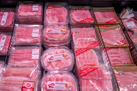 Italy - May 25, 2023: Sliced cooked ham packaged in clear plastic trays for sale in refrigerated counter inside Italian supermarketのeditorial素材