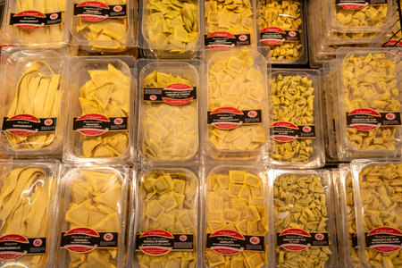 Fossano, Italy - August 14, 2023: raw fresh ravioli and agnolotti stuffed egg pasta of Italian Piedmontese cuisine in plastic packaging displayed for sale in Italian supermarketのeditorial素材