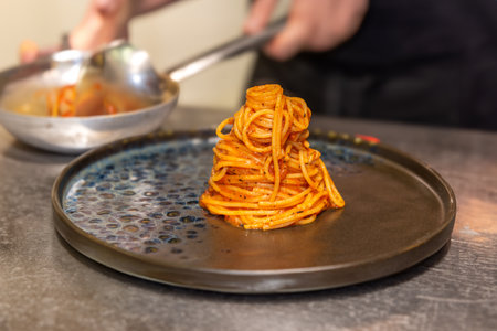 Spaghetti with tomato sauce on black plate against blurred backgroundの写真素材