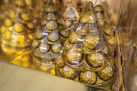 Italy - December 03, 2023: Ferrero Rocher hazelnut chocolates in transparent cone-shaped packaging in gold display for sale in Italian supermarketのeditorial素材
