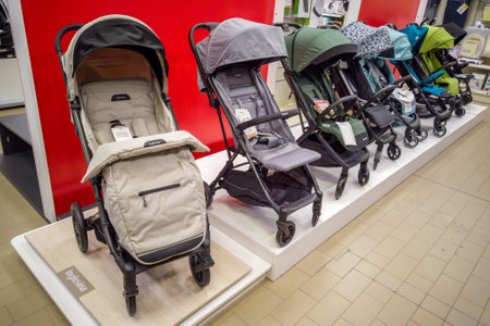 Italy - December 19, 2023: Row of baby strollers of various types displayed for sale on the shelf of...