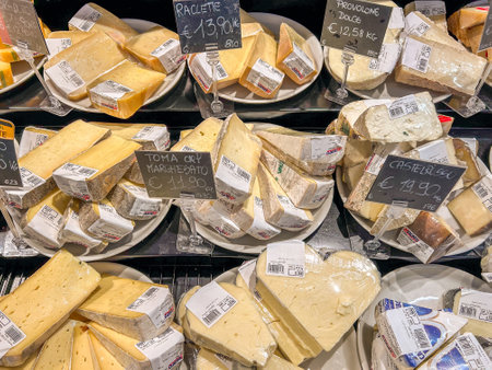 Italy - December 24, 2023: Italian cheese of various kinds cut into slices packaged and priced on display in refrigerated counter for sale in Italian supermarketのeditorial素材