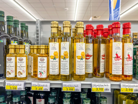 Italy - December 28, 2023: truffle and chili pepper flavored olive oil in glass bottles of various types and brands displayed on the shelf for sale in Italian supermarketのeditorial素材