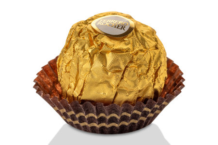 Alba, Italy - January 04, 2024: Ferrero Rocher chocolate with hazelnut filling with chocolate cream covered with hazelnut crumbs packed with golden paper, closeup with clipping pathのeditorial素材