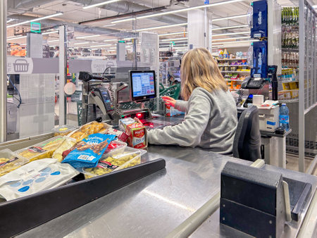 italy - January 12, 2024: Supermarket checkout with cashier passing over product reader purchased in...