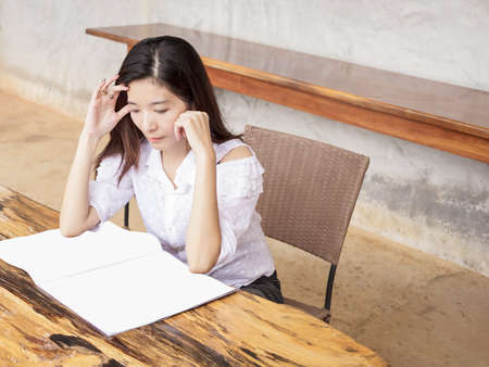 young woman reading book or magazine on wood tableの写真素材