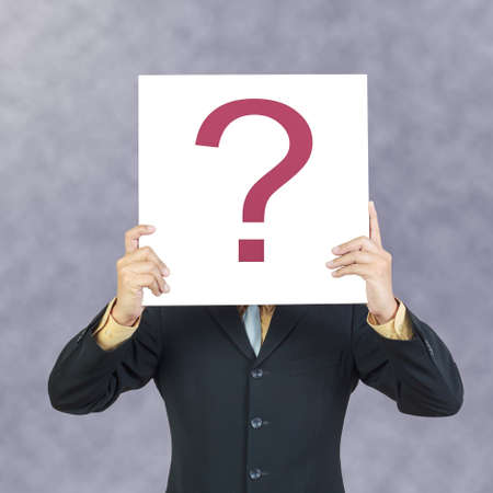 Business man holding question sign or present showing over headの写真素材