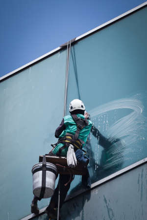 group of workers cleaning windows service on high rise buildingの写真素材