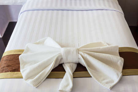 White Towel folded in bow shape on bedの写真素材