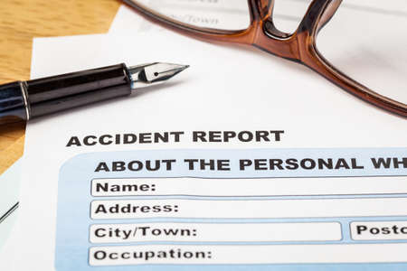 Accident report application form and pen on brown envelope and eyeglass, business insurance and risk concept; document is mock-upの写真素材