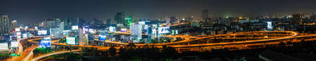 Light tail of Transportation car on road way at night life and Business Building Bangkok city area background as panorama high angle birds eye viewの写真素材