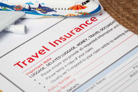 Travel Insurance Claim application form and hat with eyeglass on brown envelope, business insurance and risk concept; document and plane is mock-upの写真素材