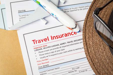 Travel Insurance Claim application form and hat with eyeglass on brown envelope, business insurance and risk concept; document and plane is mock-upの写真素材