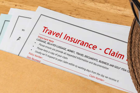 Travel Insurance Claim application form and hat with eyeglass on brown envelope, business insurance and risk concept; document is mock-upの写真素材