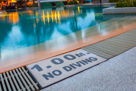 warning sign "1.00m No Diving" at Swimming pool of luxury hotelの写真素材