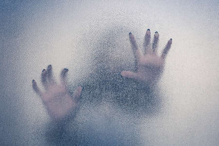 Halloween female hand behind transparent glass background as silhouetteの写真素材