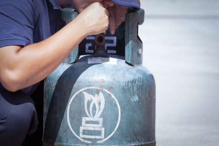 Cigarette in hand near gas tank cylinder can ignition of flammable, safety conceptの写真素材
