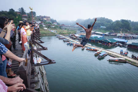 SANGKHLABURI, THAILAND - DECEMBER 27, 2015: Asia young boy jump into river from wooden bridge in morning, Sangkhlaburi District, Kanchanaburi Thailand,on December 27, 2015のeditorial素材