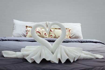towel folded in swan shape on bed sheetの写真素材