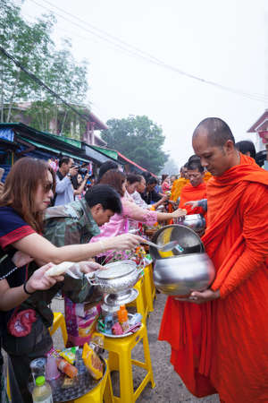 SANGKHLABURI, THAILAND - DECEMBER 27, 2015: Traveler crowd make merit with monk, in morning at...