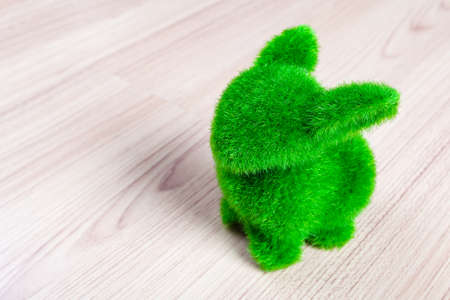 Little green rabbit on wooden floor, made from artificial grassの写真素材